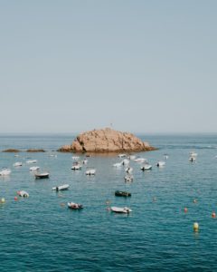 an offshore rock formation surrounded by speedboats