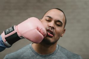 anonymous boxer punching in face of young ethnic sportsman